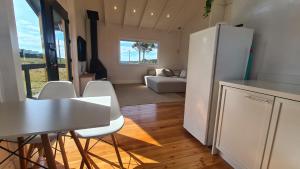 a kitchen with a white refrigerator and a table and chairs at Cabana Alpaca - Banheira, Lareira e Tranquilidade in Cambará