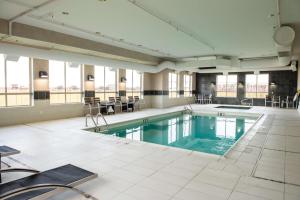a large swimming pool with tables and chairs in a building at Hampton Inn & Suites East Gate Regina in Regina