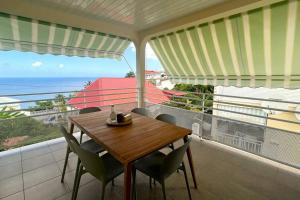 d'une table et de chaises en bois sur un balcon donnant sur l'océan. dans l'établissement Suite Spacieuse 4 étoiles 77m2 vue mer Les Saintes, à Trois-Rivières