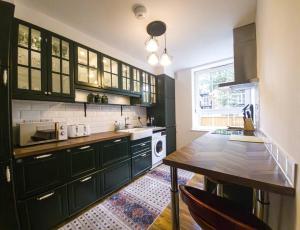 a kitchen with black cabinets and a wooden table at Cozy flat near Kings Cross in London