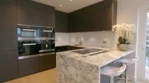 una cocina con encimera de mármol y armarios negros en Chelsea Harbour 2-Bed Apartment in London, en Londres