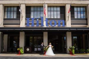 uma noiva e um noivo em pé em frente ao hotel em Hilton Asheville Biltmore Park em Asheville