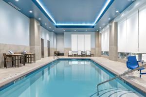 a swimming pool with a table and chairs in a hotel room at Embassy Suites By Hilton College Station in College Station