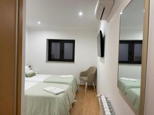 a white room with two beds and a mirror at Quinta do Sonho in Resende