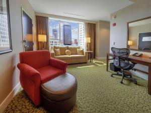 a hotel room with a desk and a chair and a couch at The Hilton Garden Inn Buffalo-Downtown in Buffalo