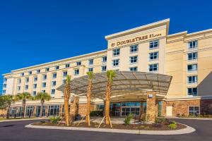 a hotel with palm trees in front of a building at DoubleTree by Hilton North Charleston - Convention Center in Charleston