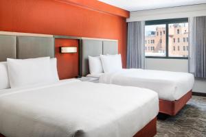 2 camas en una habitación de hotel con paredes de color naranja en SpringHill Suites by Marriott Dallas Downtown / West End en Dallas
