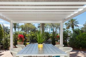 une table et des chaises bleues sous une pergola blanche dans l'établissement Hilton Garden Inn Daytona Beach Airport, à Daytona Beach