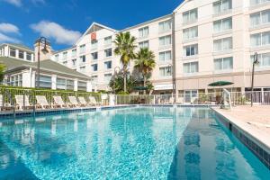 a large swimming pool in front of a hotel at Hilton Garden Inn Daytona Beach Airport in Daytona Beach