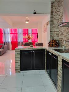 - une cuisine avec des armoires noires et des rideaux rouges dans l'établissement Hotel boutique CVC, à Acapulco