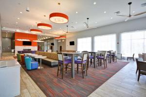 uma cafetaria com mesas, cadeiras e janelas em Homewood Suites by Hilton Orlando Theme Parks em Orlando