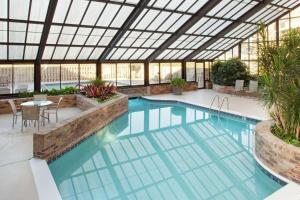 uma piscina interior com um jardim de Inverno com tecto de vidro em DoubleTree by Hilton Hotel Oak Ridge - Knoxville em Oak Ridge