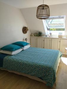 a bedroom with a bed with blue pillows and a window at Le Clos des Mouettes in Calais