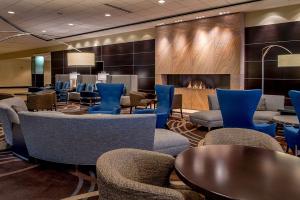 a waiting room with chairs and tables and a fireplace at Hilton St. Louis at the Ballpark in Saint Louis