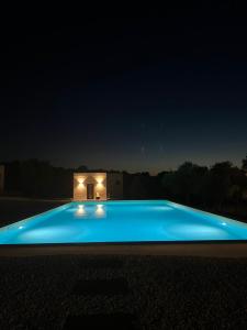 a blue swimming pool at night with a house in the background at Agriturismo La Croisette in Dorgali