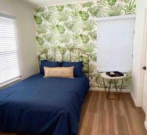 a bedroom with a blue bed with a tropical wallpaper at Crown Point Home w/ Cowboy Pool 2 Blocks to Bay in San Diego