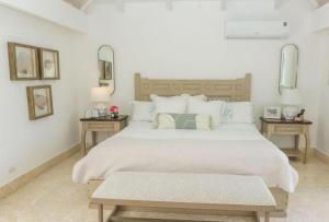 a white bedroom with a large bed with two tables at Sunny Vacation Villa No 92 in San Rafael del Yuma