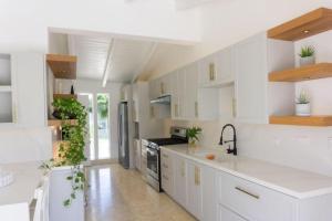 a white kitchen with white cabinets and plants in it at Sunny Vacation Villa No 92 in San Rafael del Yuma