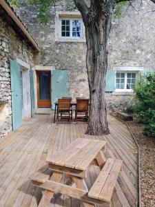 una terraza de madera con una mesa y un árbol en Maison provençale, jardin arboré et terrasses proche Grignan 8-10pers, en Réauville