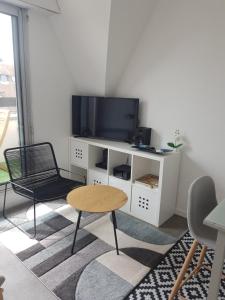 uma sala de estar com uma televisão e uma mesa e cadeiras em Appartement Liza 2 pièces Vue Mer à Cabourg em Cabourg