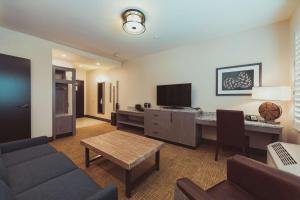 a living room with a couch and a desk with a television at Tailwater Lodge Altmar, Tapestry Collection By Hilton in Pulaski