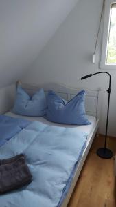 Una cama con almohadas azules y una lámpara en una habitación. en Casa Luna, en Donnerskirchen