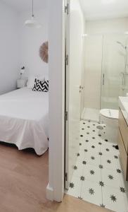 een slaapkamer met een bed en een badkamer met een douche bij La buhardilla in Sevilla