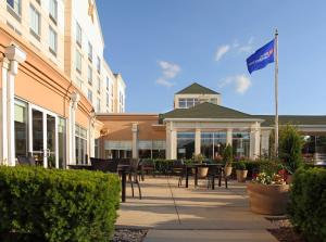a building with a flag and tables and chairs at Hilton Garden Inn Frederick in Frederick