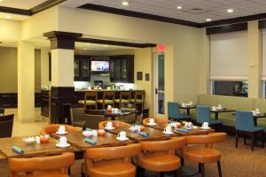 Hilton Garden Inn Frederick في فريدريك: غرفة طعام مع طاولات وكراسي خشبية