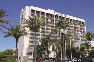 a hotel building with palm trees in front of it at DoubleTree by Hilton Torrance - South Bay in Torrance