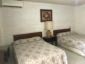 um quarto com 2 camas e uma parede de tijolos em Hotel las hamacas em Acapulco