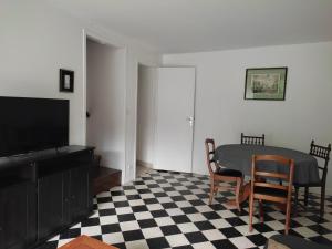 ein Wohnzimmer mit einem Tisch, Stühlen und einem TV in der Unterkunft Les Glycines in Vulaines-sur-Seine