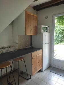 - une cuisine avec un comptoir et deux tabourets dans l'établissement Les Glycines, à Vulaines-sur-Seine