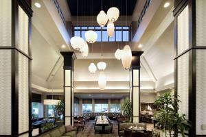 a lobby with tables and chairs and chandeliers at Hilton Garden Inn Auburn Riverwatch in Auburn