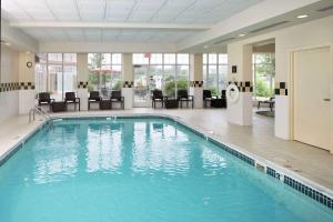 a swimming pool in a hotel lobby with chairs and tables at Hilton Garden Inn Auburn Riverwatch in Auburn