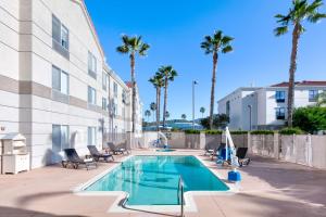 a swimming pool in front of a building with palm trees at Hilton Garden Inn Irvine East/Lake Forest in Foothill Ranch