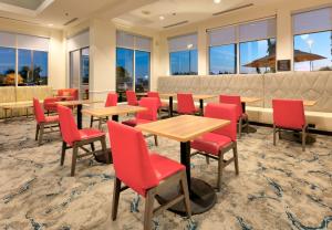 un restaurante con sillas rojas, mesas y ventanas en Hilton Garden Inn Irvine East/Lake Forest en Foothill Ranch