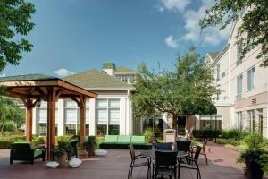 un patio con cenador, mesas y sillas en Hilton Garden Inn Tulsa Airport, en Tulsa