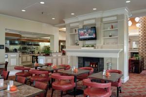 a restaurant with tables and chairs and a fireplace at Hilton Garden Inn Tulsa Airport in Tulsa