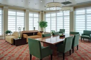 una sala de conferencias con mesa de madera y sillas verdes en Hilton Garden Inn Tulsa Airport en Tulsa