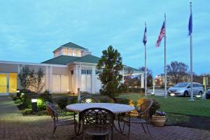 uma mesa e cadeiras em frente a um edifício com bandeiras em Homewood Suites by Hilton Chesapeake - Greenbrier em Chesapeake