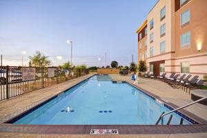 坦培的住宿－亞利桑那州菲尼克斯/坦佩亞利桑那州立大學地區希爾頓花園酒店，一座带椅子的大型游泳池和一座建筑