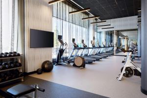 einen Fitnessraum mit einer Reihe von Trainingsgeräten und einem Flachbild-TV in der Unterkunft Hilton Garden Inn Montreal Midtown, Quebec, Canada in Montreal
