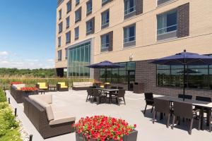 un patio avec des tables et des parasols en face d'un bâtiment dans l'établissement Hampton Inn & Suites Grand Rapids Downtown, à Grand Rapids