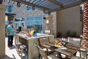 a man standing on a patio with a table and chairs at Homewood Suites By Hilton Los Angeles Redondo Beach in Redondo Beach