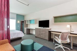 a hotel room with a bed and a desk with a television at Home 2 Suites By Hilton Indianapolis Northwest in Indianapolis