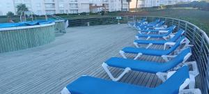 a row of blue and white lounge chairs on a deck at Laguna Bahia Algarrobo in Algarrobo