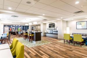 オクラホマシティにあるHampton Inn Oklahoma City Northeast OKのロビーには黄色い椅子とテーブルが備わるカフェテリアがあります。