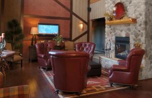 sala de estar con sillas de cuero y chimenea en Thumper Pond Resort, en Ottertail