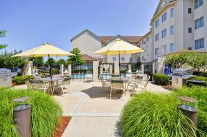 a patio with tables and chairs and umbrellas at Homewood Suites by Hilton Tulsa-South in Broken Arrow